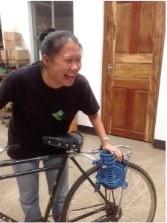 Jodie Wu laughing beside a bicycle fitted with the pedal-powered maize sheller