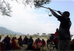 A community gathers outdoors as a solar lamp is held up for demonstration